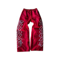Y2K nylon track pants in red with bold white lettering, featuring a baggy silhouette and elastic waistband.