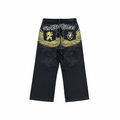 Faded black denim baggy jeans with yellow wing embroidery and heraldic lion motifs in Y2K style