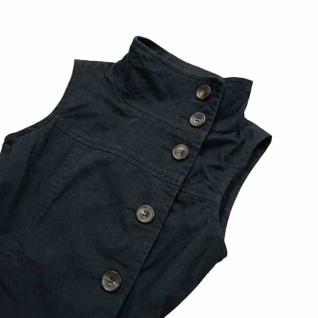 black structured sleeveless vest with high neck and asymmetrical buttons
